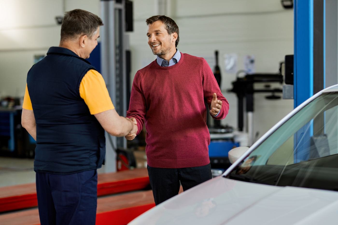 Profissional da oficina cumprimentando um cliente na entrega do carro