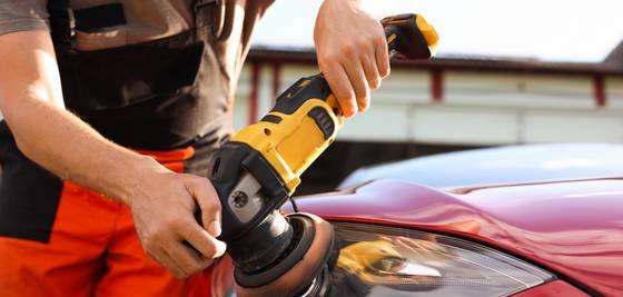 Profissional polindo a lateral de um carro vermelho com politriz